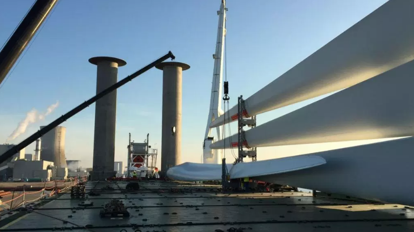 Windturbineonderdelen en hijskraan op een havenkade