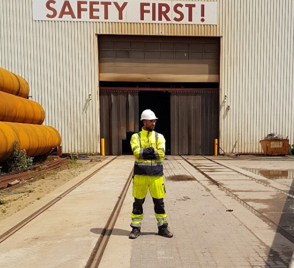 Werknemer in veiligheidskleding voor een loods met de tekst Safety First